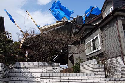 住宅側から見た被害のようす、倉庫の建物の一部が屋根の上に