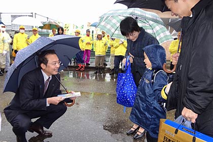 三条市立大崎小学校で春の交通安全運動出発式と新一年生交通安全キャンペーン、新1年生にちらしなどを手渡す国定市長(左)