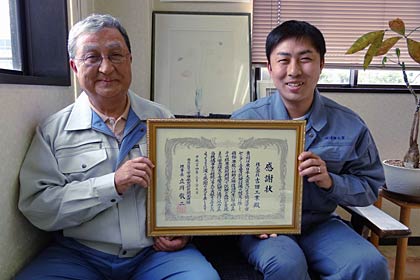 JAXAからの感謝状を手に左が吉田社長、右が吉田専務