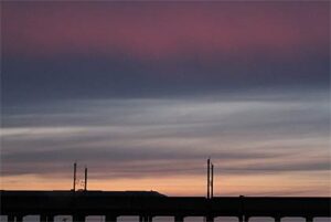 17日夕方、三条市上須頃地内からやわらかない色のグラデーションを描いた夕焼けと燕三条駅へ滑り込む上越新幹線