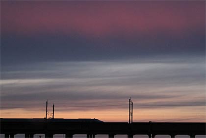 17日夕方、三条市上須頃地内からやわらかない色のグラデーションを描いた夕焼けと燕三条駅へ滑り込む上越新幹線