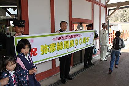 「弥彦線開業90周年号」の乗客を横断幕を掲げて歓迎