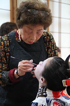 厳しい表情で紅をさす竹内さん