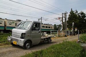 事故のあったJR信越本線の神明様踏切、列車とぶつかった軽トラック（後に写っている列車はぶつかった列車ではない）