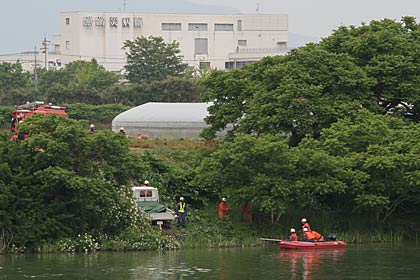 対岸の三条市大島地内から燕・弥彦消防本部が救助艇で捜索するようす、奥の建物は燕労災病院