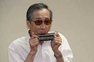 地域交流スペース「つばめの茶の間仲町」で全盲のハーモニカ奏者、大橋靱彦さんが演奏する懐メロに集まったお年寄りは笑顔がいっぱい