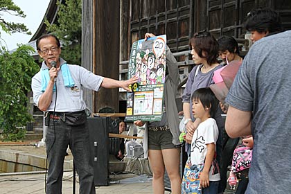 家族4人の似顔絵が次回の三条マルシェのポスターにデザインされることを発表する箕輪三条マルシェ実行委員長