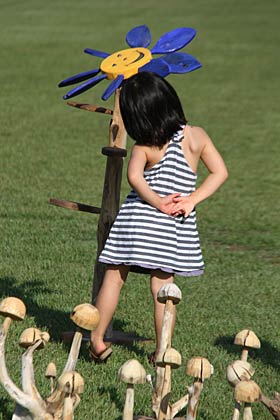 23日、三条市総合運動公園で開かれている「第5回三条クラフトフェア in 槻の森」でおとぎの国の花のような不思議なオブジェに首をかしげて見入る女の子