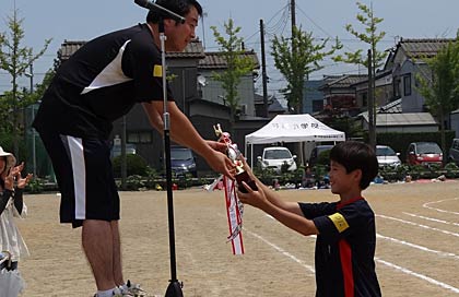  大山会長から1位の中部チームの代表児童に優勝トロフィー