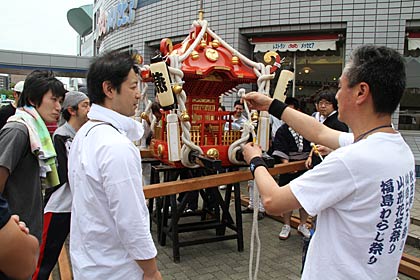  後輩を指導しながらみこしに掛矢を使って担ぎ棒の取り付け