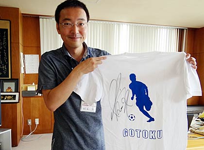 酒井選手の自筆サイン入りTシャツを市役所にも持ってきて広げて見せる国定市長