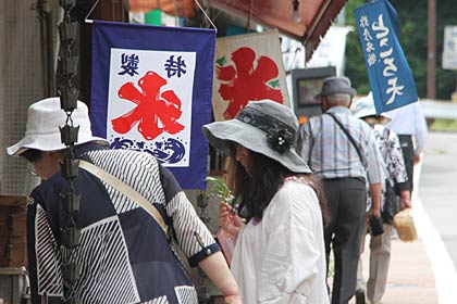  梅雨明けした18日、弥彦の土産屋の軒先に氷旗や「ところ天」の旗が揺れる