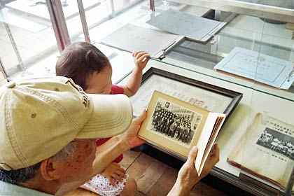 自分が小学生だったころの写真を孫に見せるおじいさん
