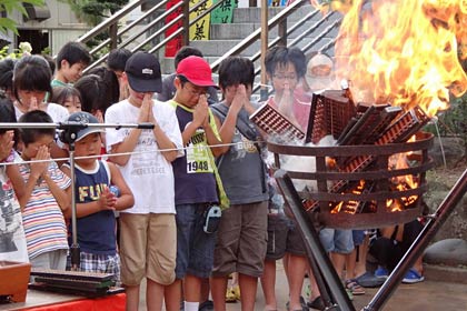 そろばんが燃える火に手を合わせる子どもたち