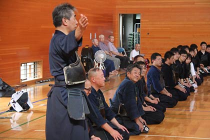 部旗を指し示して後輩を激励する光明館館長の草間範士