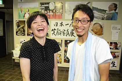 笑顔写真家かとうゆういちさん(右)とタイトルの書などを書いた大学の後輩の小笠原麗さん、かとうさんの写真に写っている笑顔に負けないような笑顔を見せてくれる