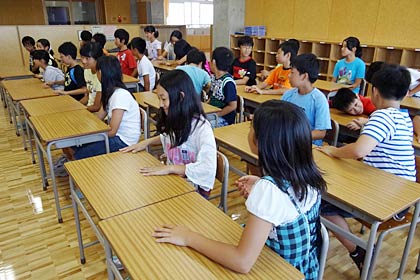 新しい校舎に新しい机、いすに笑顔の児童