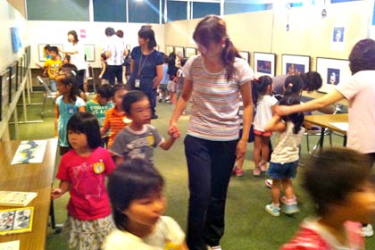 7日から23日まで燕市立図書館で開かれている村上康成絵本原画展の初日、オープニングのテープカットに訪れて作品を見学する燕保育園と南保育園の園児