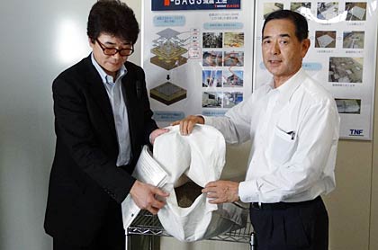  建物の下に敷き詰める土のうを示す外山産業の外山社長