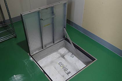 倉庫の床を開くと敷き詰めた土のうが見える