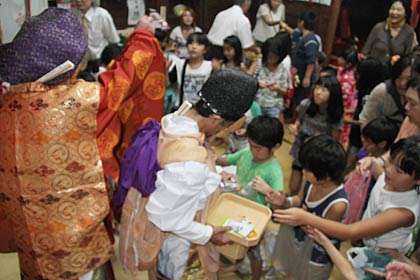 「福神遊の舞」の最後に子どもたちに菓子をまく恵比寿と大黒