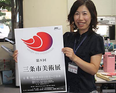 第8回三条市美術展のポスターを手に出品を呼びかける市の担当者