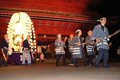 県の文化財に指定されている「本成寺三門」の前を万灯行列が行く