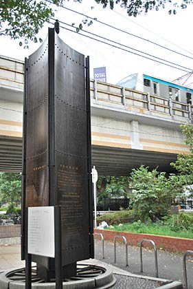 「鉄道発祥の地記念碑」の後ろを今の電車が走る