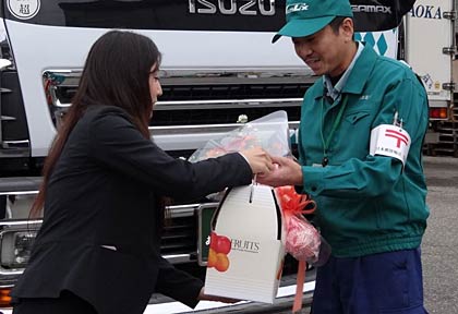 出発するトラックのドライバーにJA職員から花束を贈る