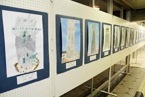 28日まで燕市総合文化センターロビーに展示されている子ども写生会「水道の塔を描こう」に参加した小学生17人が描いた水道の塔