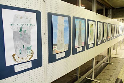 28日まで燕市総合文化センターロビーに展示されている子ども写生会「水道の塔を描こう」に参加した小学生17人が描いた水道の塔