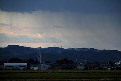 7日夕方、三条市塚野目地内から東の空には雨雲の下に降る雨がレースのカーテンのように筋になって見え、すぐ近くには青空ものぞいた