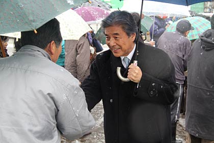 雪降る中を集まった人たちと握手する中曽根参院議員