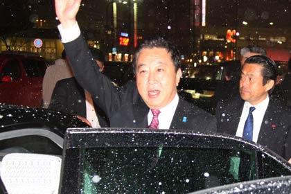 演説を終わって雪のなか手を降って車に乗り込む野田首相