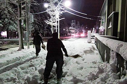 9日夜、市役所前の歩道を除雪する