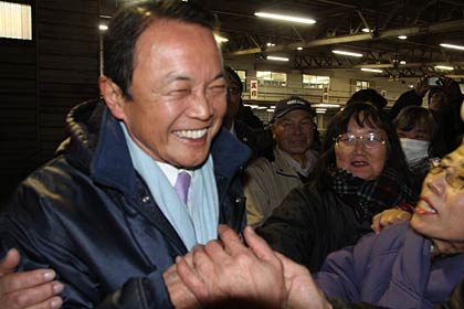 握手を求める聴衆にもみくちゃにされる麻生氏