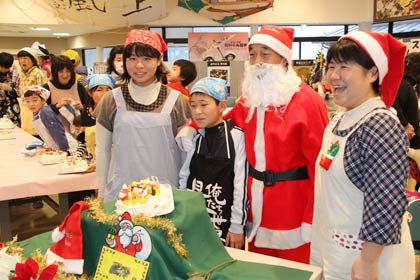 道の駅国上のふれあいパーク久賀美でクリスマスケーキ作り体験教室、作ったケーキを前にサンタクロースと並んで記念写真