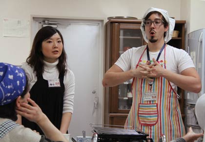 調理実習を指導する三条市国際交流員ピーター・カーターさん(右)と手伝った妻の鄭優佳さん(左)