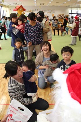 三条市子育て拠点施設「すまいるランド」で20日開かれたクリスマス会で順番にサンタクロースからプレゼントをもらう親子