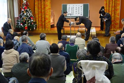 広域養護老人ホーム「県央寮」で角利産業の加藤社長から深々と頭を下げて目録を受け取る国定市長