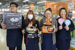 新春初売りのガラポン抽選会で当たる商品を手にストックバスターズのスタッフ