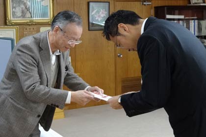 国定市長に1億円の小切手を包んだのし袋を手渡す(株)高儀の高橋社長