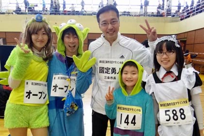 新設の仮装の部の出場者と一緒に記念写真に写る国定三条市長