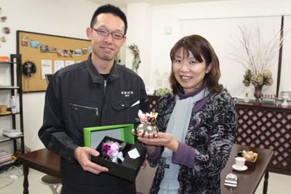 フラワーアレンジメントスクール「スノードロップ」で、アレンジメント体験教室で使う花器にプリザーブドフラワーを組み合わせた商品「KALEN」を手に「スノードロップ」の加藤代表(右)と「KALEN」を企画した「雑貨創造」の田中代表(左)