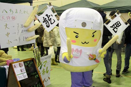 栃尾のゆるキャラ「あぶらげんしん」もヘチマたわし手にPRに一役買う