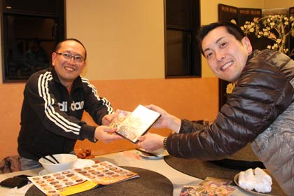 燕三条ラーメン王国国王の梨本さん(右)が「三条カレーラーメン」のプロモーションDVDを受け取る高橋さん