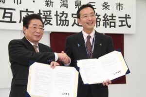 災害時の相互応援協定を結んで握手する立谷相馬市長(左)と国定三条市長