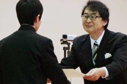 ほほえんで卒業生に卒業証書を手渡す宮下校長