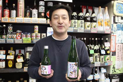 右手に吟醸「きららん」、左手に清酒「分水桜まつり」を持つコメゴ酒店の古沢さん