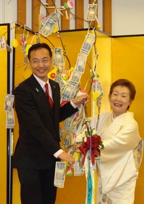 国定市長に善意の下がったまゆ玉飾りを手渡す「スナックマンマ」の五十嵐さん